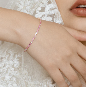 The Pink Sapphire and White Diamond Tennis Bracelet, a laced lady wearing tiny cut diamond gemstones, and pink sapphire bracelet