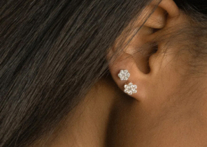 Flower Diamond Stud Earrings with 0.5 Carats, an ear wearing 2 flower shaped earrings with diamond gemstone