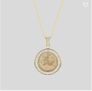 A round necklace pendant bordered with diamonds and in the center is an engraved capricorn zodiac sign. .