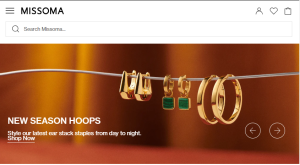 Missoma jewlery's homepage banner freaturing new season hoops. there are three pairs of gold hoop earrings on a wire.
